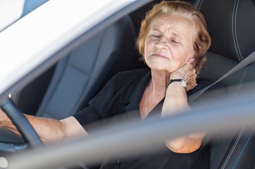 Elderly woman holds her neck due to whiplash in a car accident