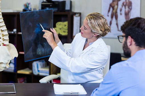 Chiropractor Examining X-Ray of man with a disc herniation