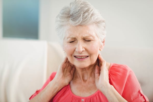 Senior woman suffering from neck pain at home